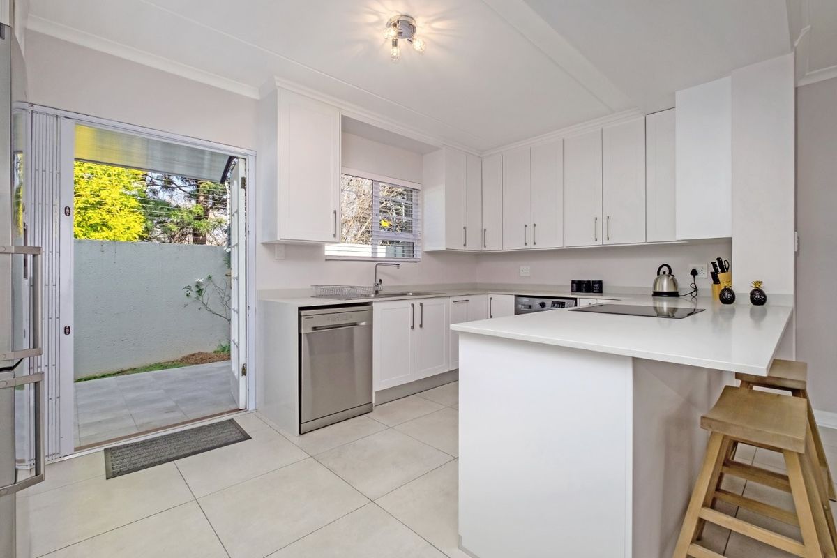 Modern kitchen featuring white cabinetry, stone countertops, integrated hob, and direct access to a private outdoor patio area.