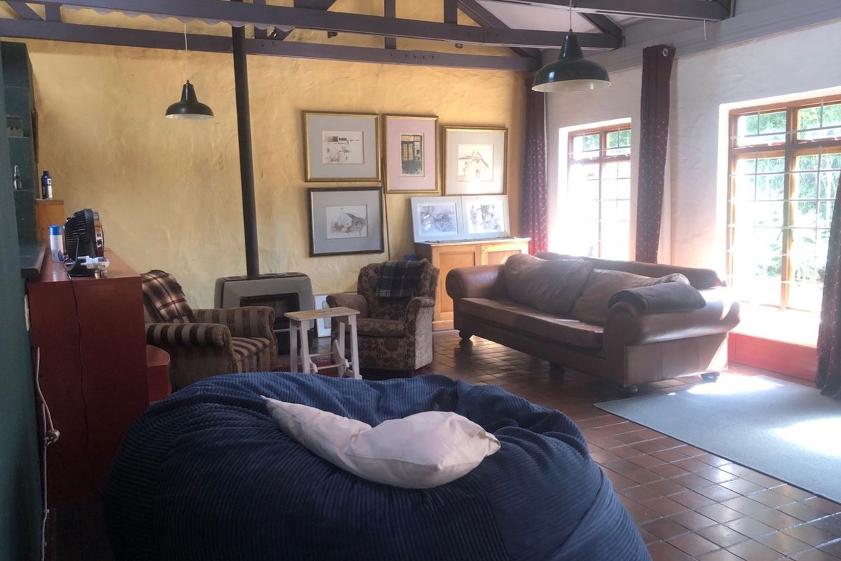 Spacious living room featuring exposed timber roof trusses, a built-in wood-burning fireplace, and large windows providing ample natural light.