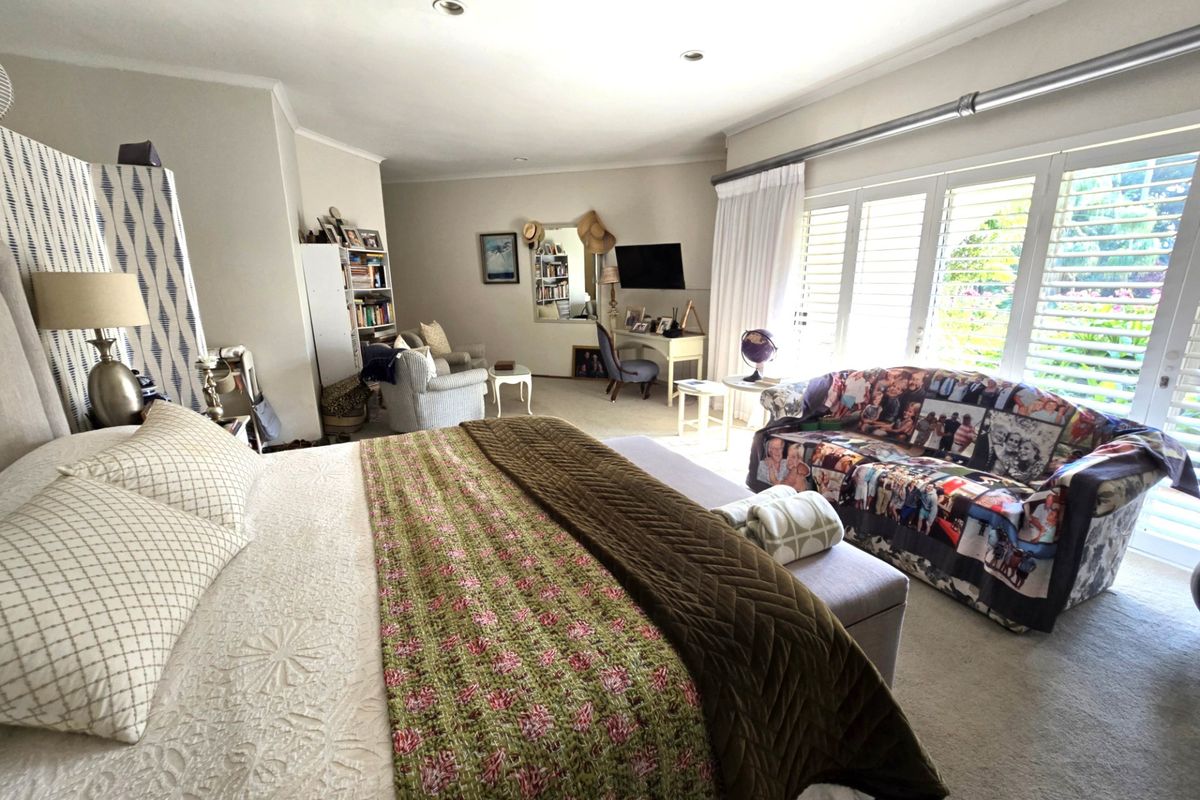 Spacious bedroom featuring neutral carpeting, recessed lighting, and large sliding glass doors with plantation shutters providing ample natural light.