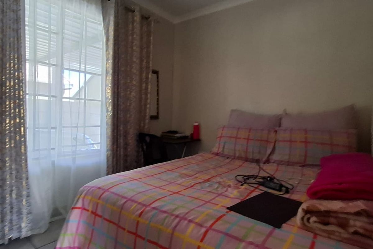 A standard bedroom featuring tiled flooring, a window with security bars, and coved ceiling detailing.