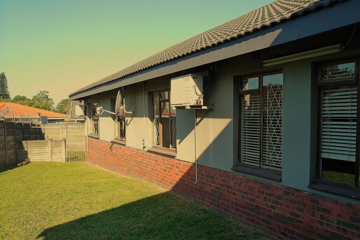 A view of the rear exterior elevation featuring a brick and plaster facade, tiled roof, and wall-mounted air conditioning unit.