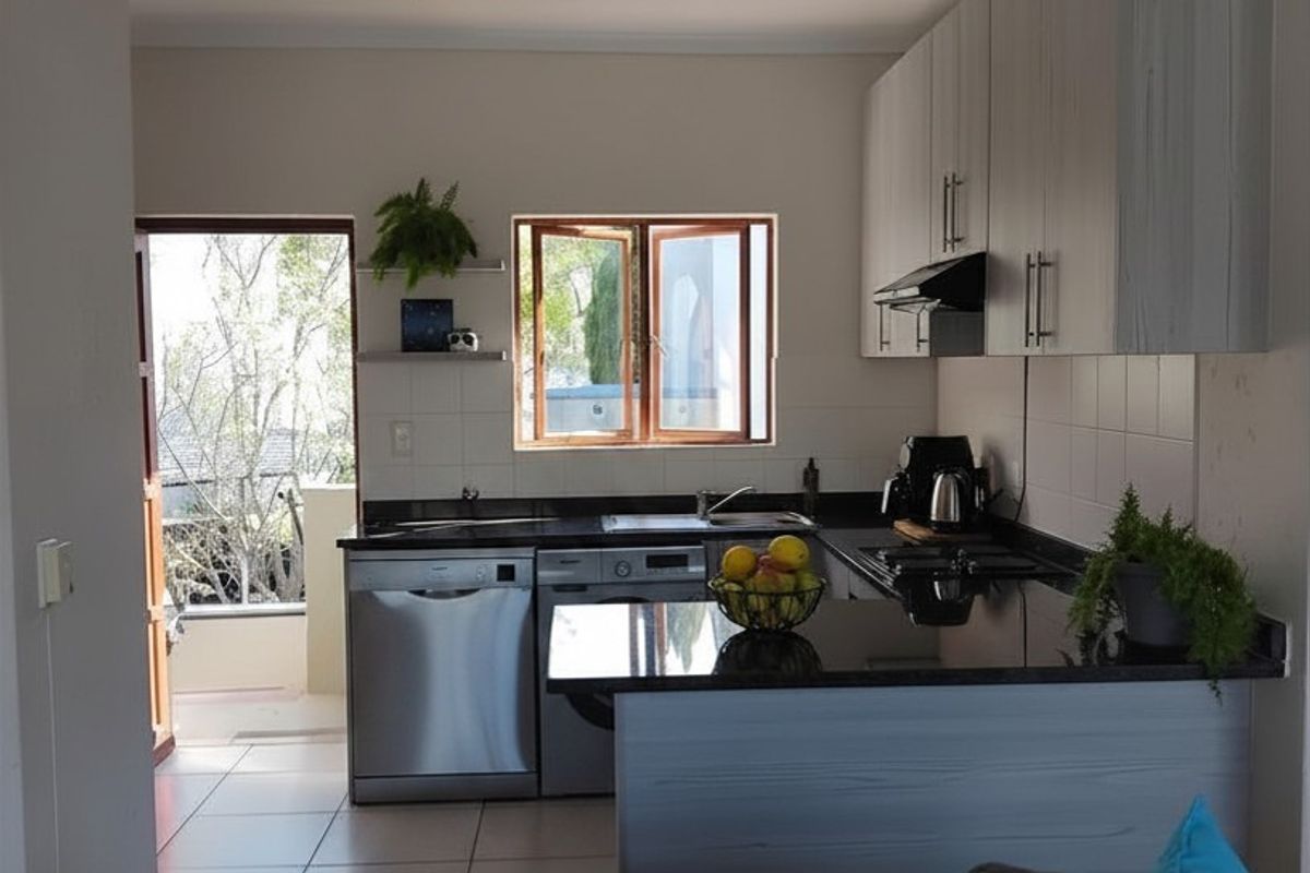 A functional kitchen featuring dark granite countertops, light-toned cabinetry, a built-in hob, and an integrated dishwasher, with direct access to an outdoor area.