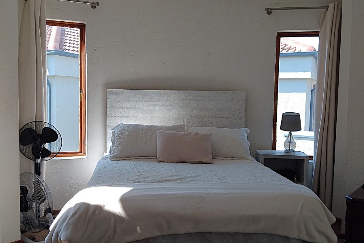 A bedroom featuring a curved wall design with dual windows, providing natural light and a cozy atmosphere.