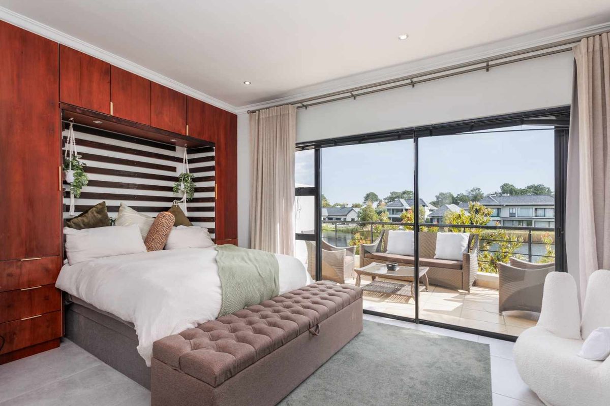 Spacious bedroom featuring built-in wooden cabinetry, recessed lighting, and large sliding glass doors opening onto a private balcony with scenic views.