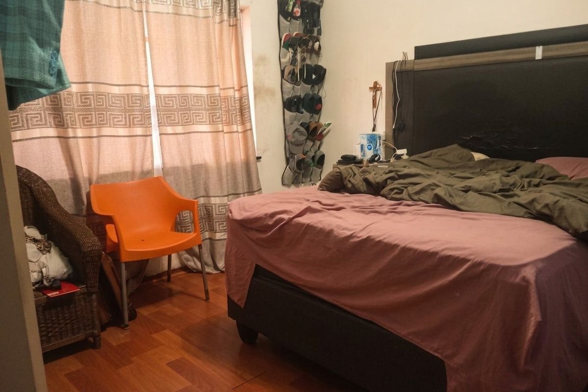 A bedroom featuring wood-look flooring and a window with curtains.