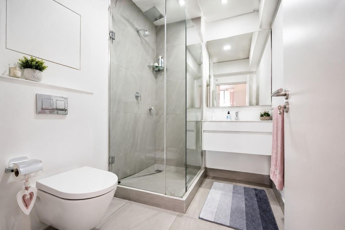 Modern bathroom featuring a glass-enclosed walk-in shower, wall-mounted toilet, and a sleek floating vanity with a large mirror.