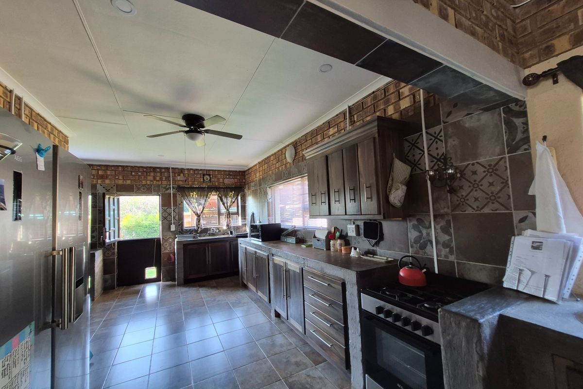 A rustic-style kitchen featuring dark wood cabinetry, exposed brick wall accents, tiled flooring, and a built-in gas stove with an integrated oven.