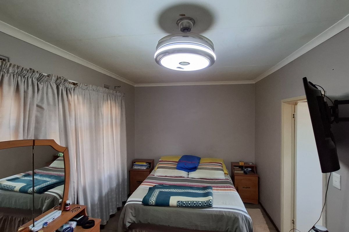 A standard bedroom featuring a central ceiling fan light fixture, curtain tracks, and a wall-mounted television bracket.