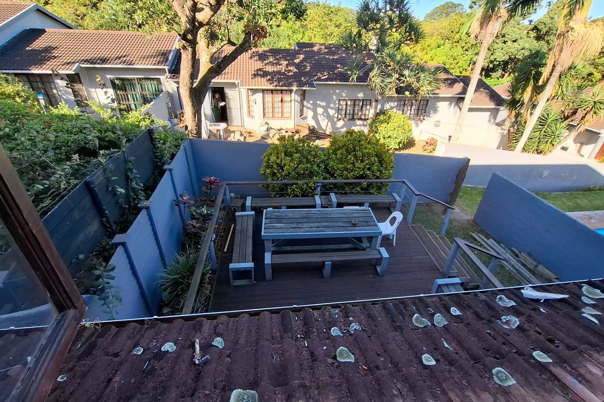 Elevated view of a rear courtyard featuring a timber deck, perimeter boundary walls, and access to the main townhouse structure.