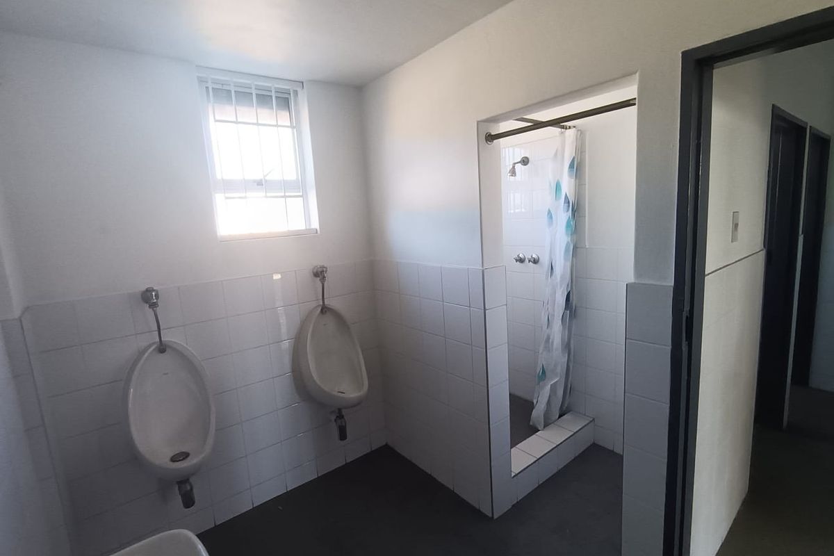 Commercial restroom facility featuring wall-mounted urinals, a tiled shower enclosure, and functional plumbing fixtures.