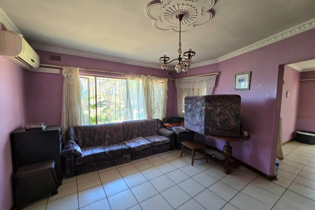 A living room featuring tiled flooring, a decorative ceiling rose with a chandelier, and a wall-mounted air conditioning unit.