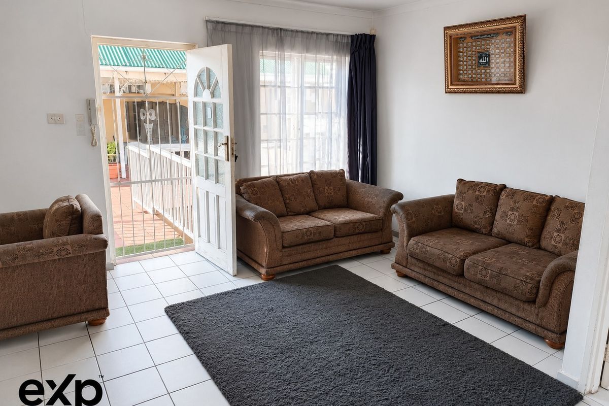 A bright living room featuring tiled flooring and direct access to an outdoor patio area through a security gate.