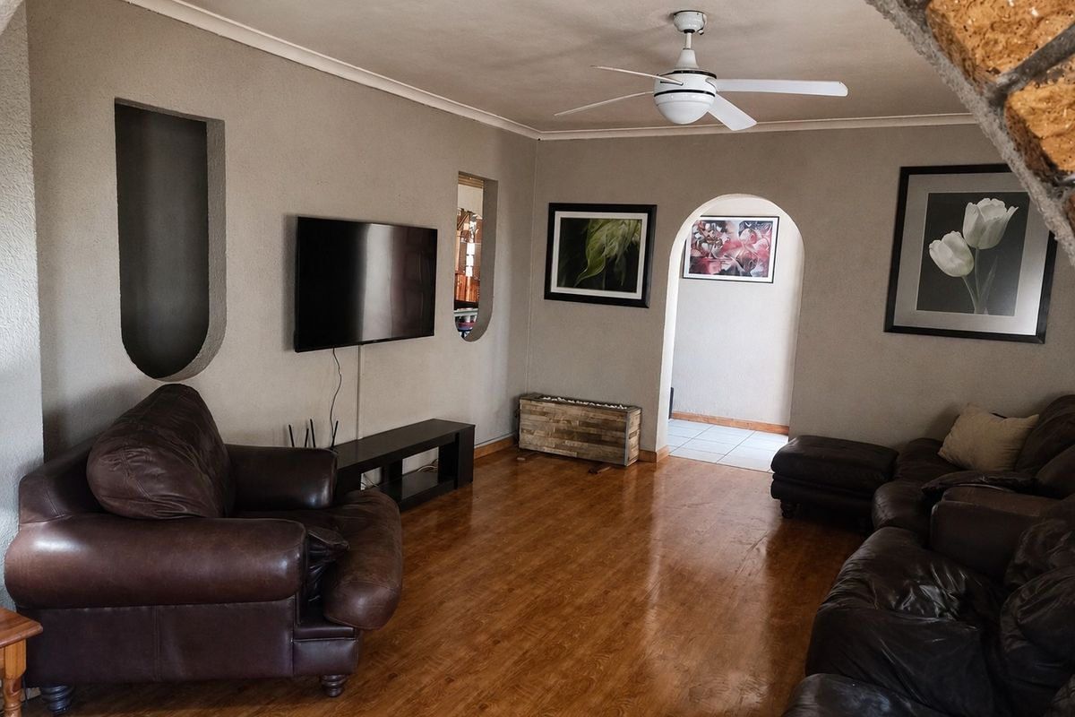 A comfortable living room featuring laminate flooring, a ceiling fan, and unique architectural archways with recessed wall niches.