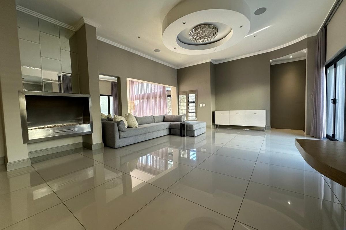Spacious living room featuring polished porcelain tiles, a modern built-in fireplace, and a sophisticated recessed ceiling design with integrated lighting.