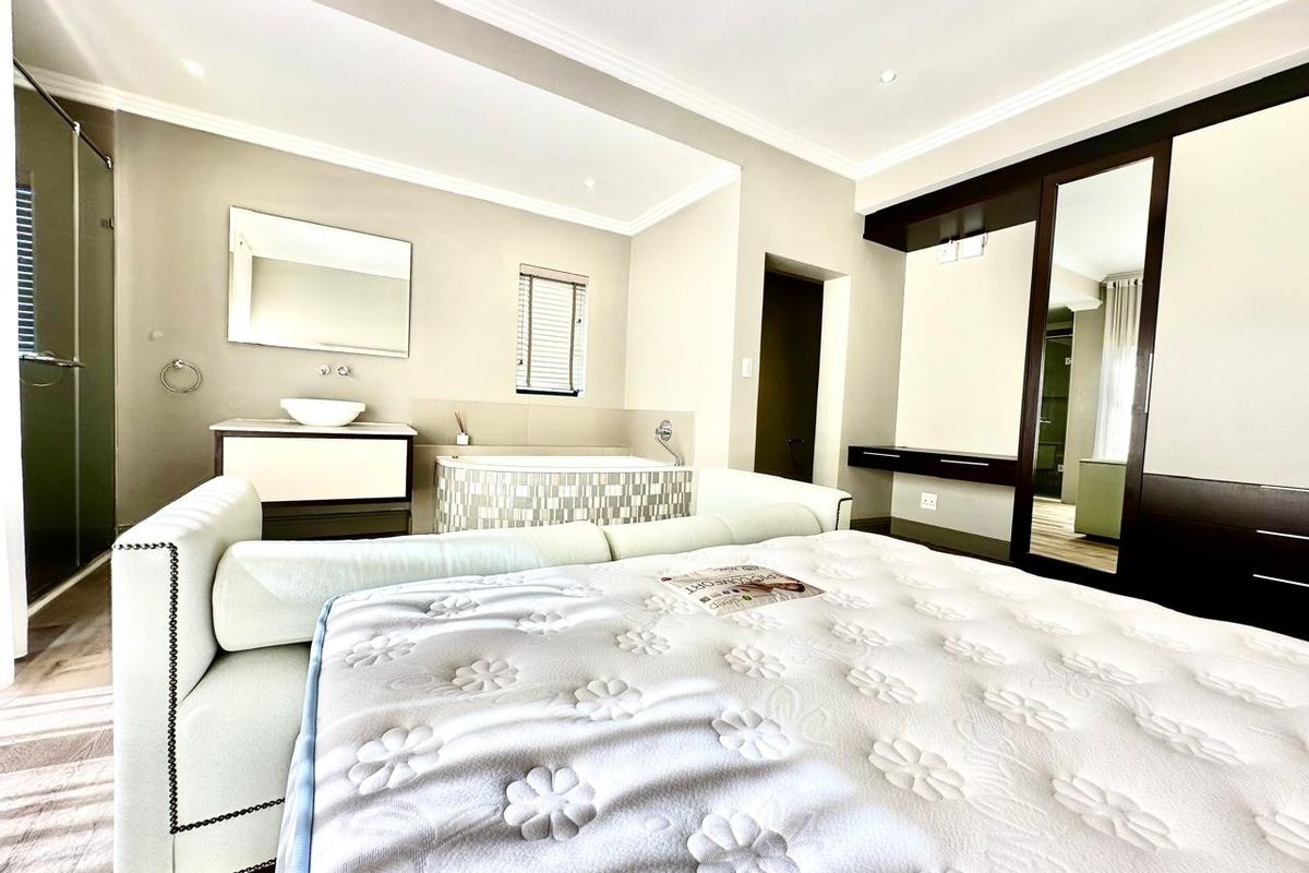 Spacious bedroom featuring an integrated en-suite bathroom area with a built-in bathtub, vanity, and extensive built-in cupboard storage.