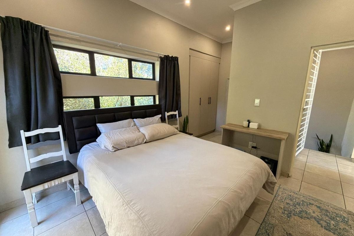 A functional bedroom featuring tiled flooring, built-in cupboards, and a horizontal window providing natural light.