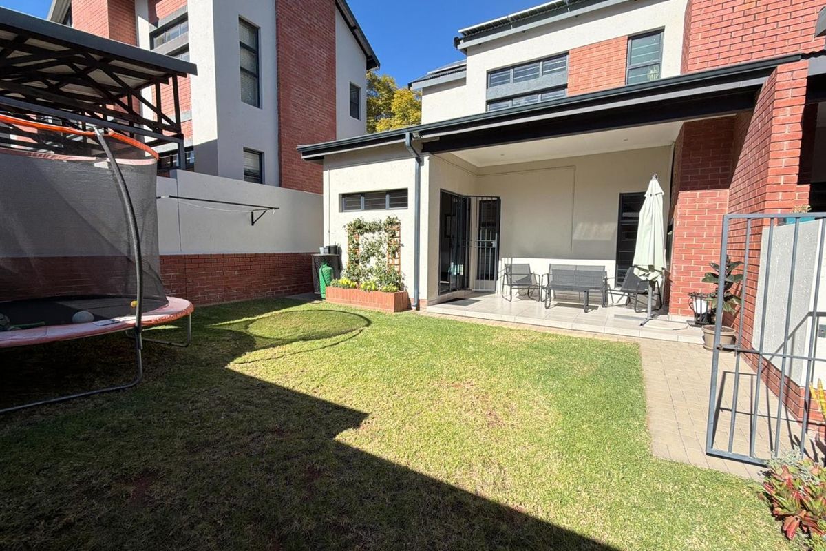 A private rear garden featuring a covered patio area, paved walkway, and a well-maintained lawn, perfect for outdoor relaxation.
