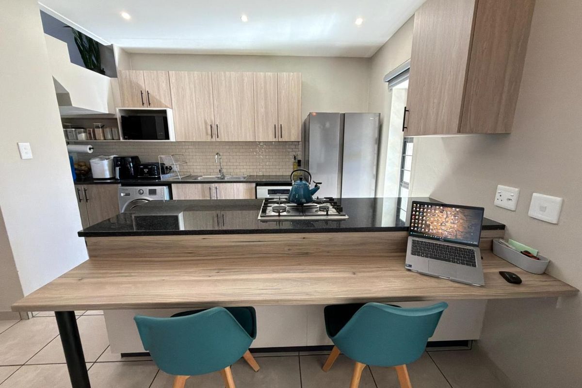 Modern kitchen featuring light wood cabinetry, granite countertops, a gas hob, and an integrated breakfast bar, providing a functional and contemporary cooking space.