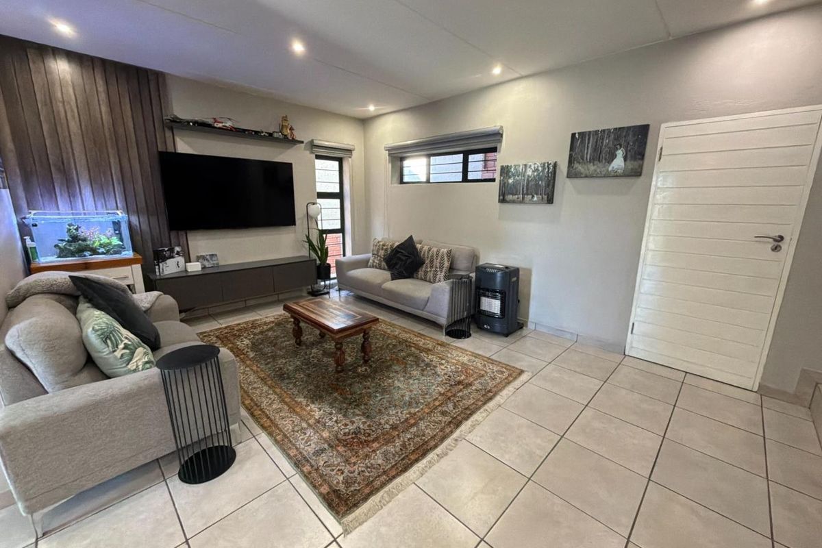 A well-maintained living room featuring tiled flooring, recessed downlighting, and a decorative feature wall panel, providing a comfortable and functional living space.