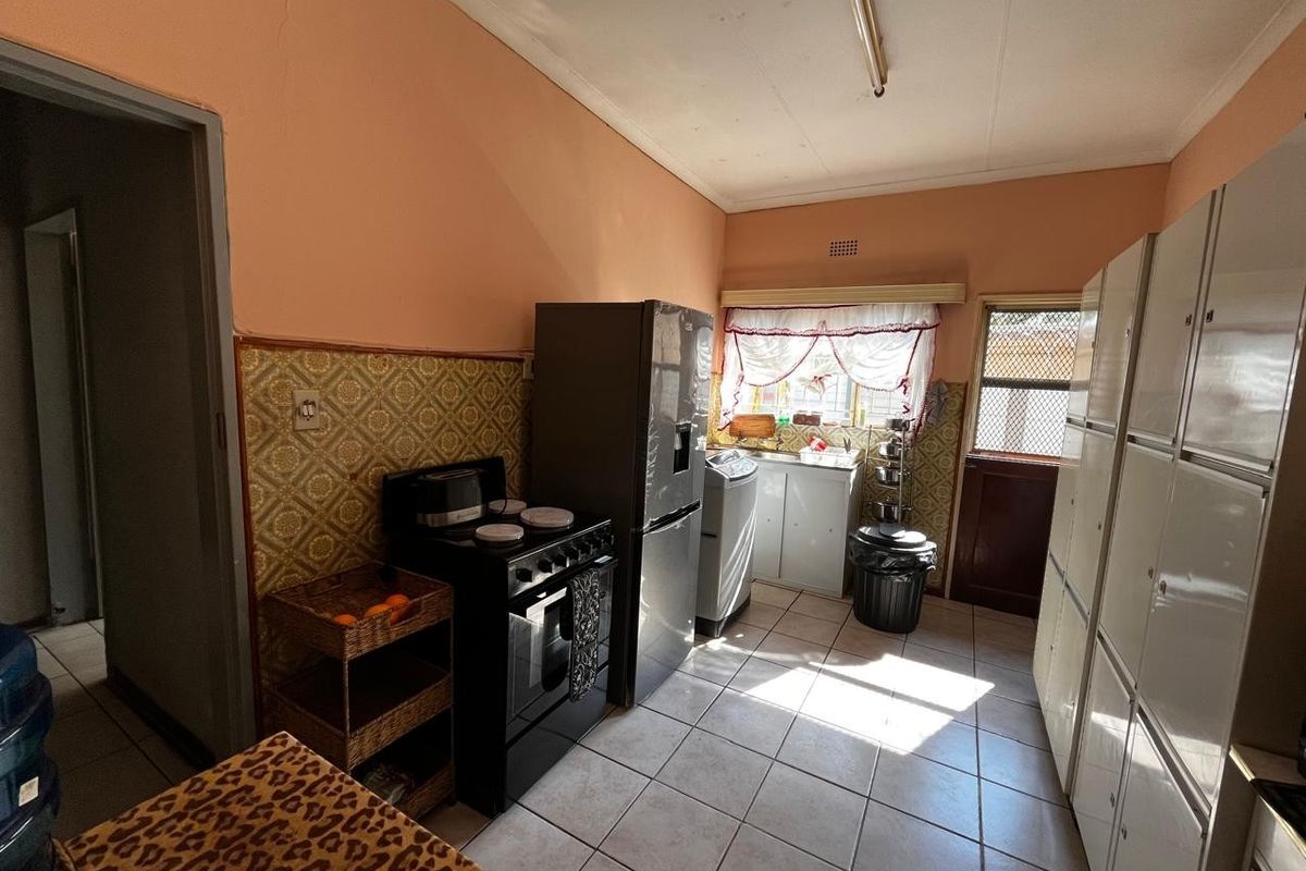A functional kitchen featuring tiled flooring, built-in cabinetry, and a freestanding stove, offering a practical layout with potential for modernization.