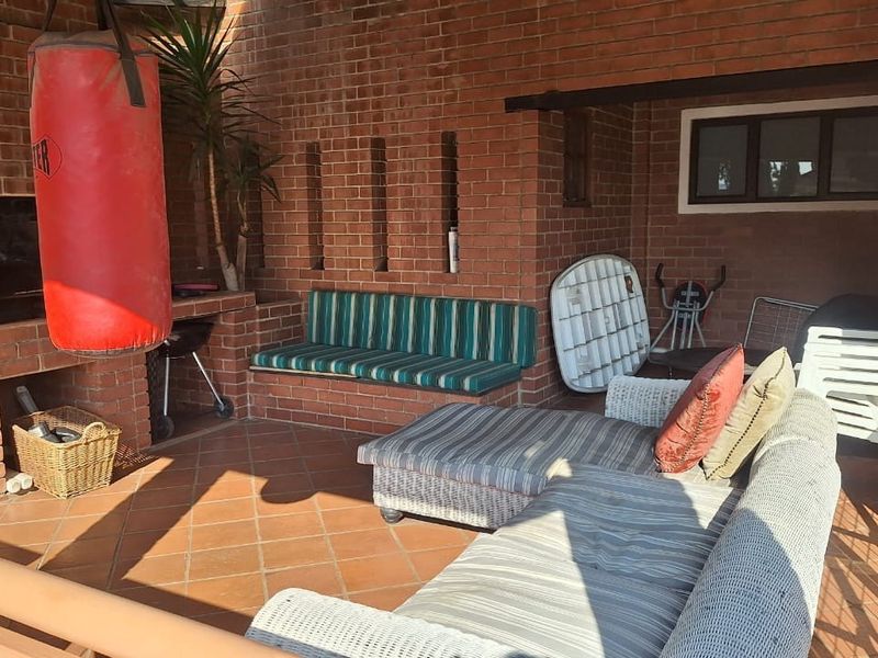 Covered patio area featuring a built-in brick braai and integrated brick seating, providing a functional outdoor entertainment space.