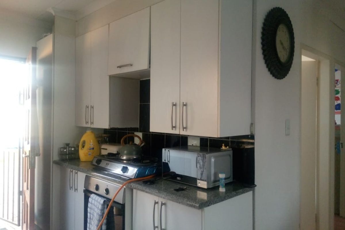 A functional kitchen featuring white cabinetry, granite-style countertops, and a built-in oven with a gas hob.