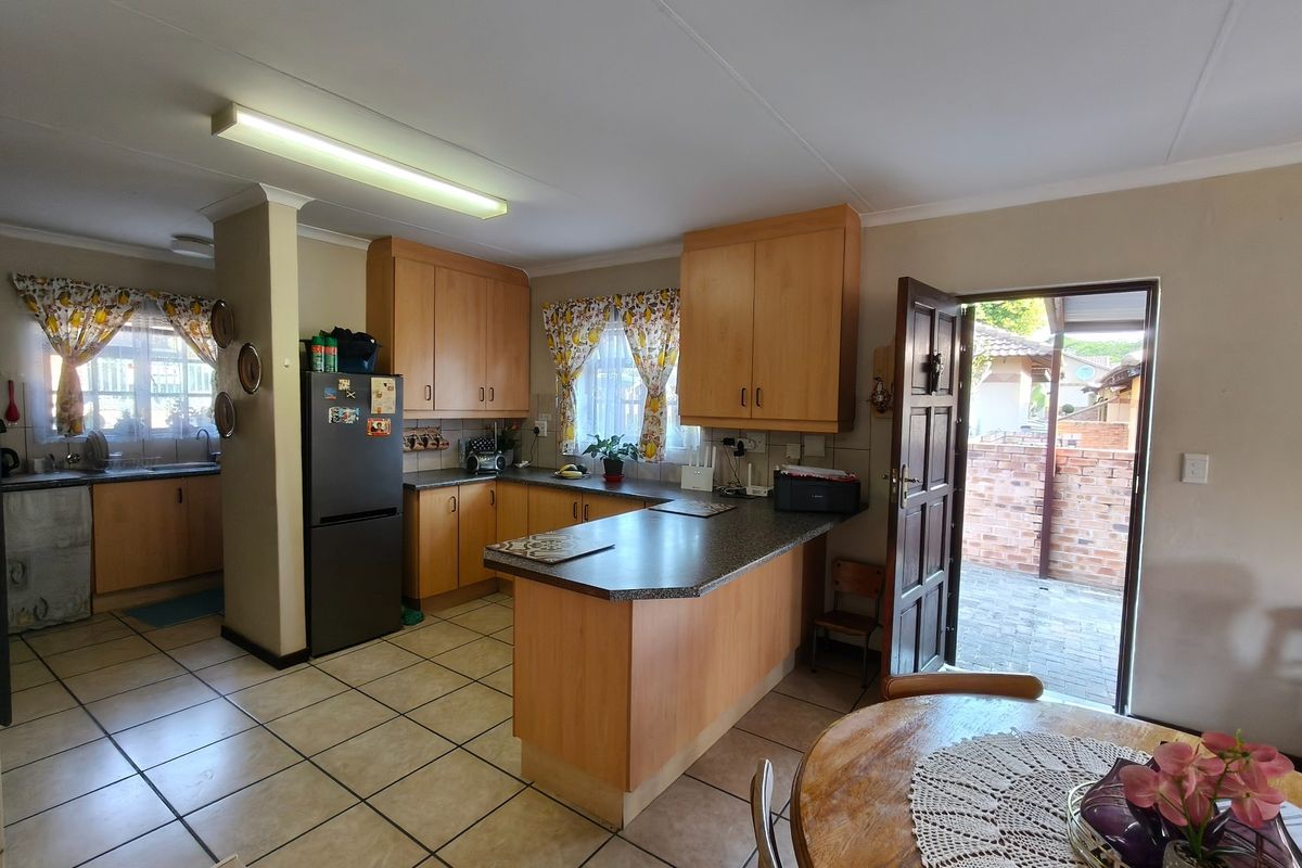 A functional kitchen featuring light wood cabinetry, laminate countertops, and a breakfast bar, with direct access to an outdoor patio area.