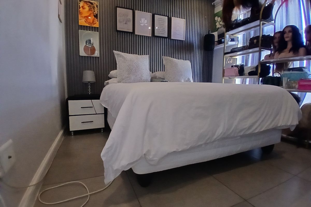A well-maintained bedroom featuring a modern vertical slat feature wall and neutral floor tiling.