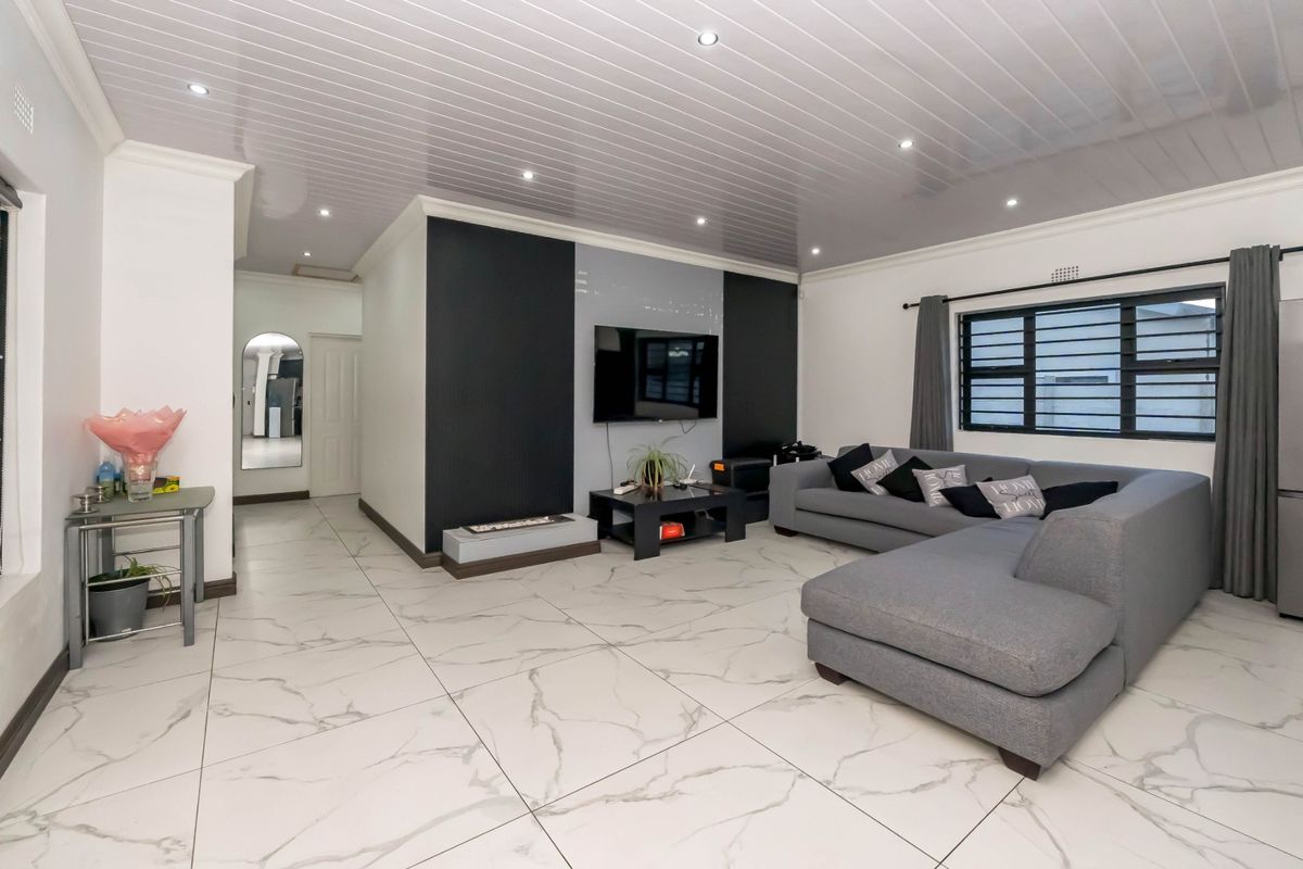A modern living room featuring large format marble-look floor tiles, a sleek built-in fireplace, and recessed ceiling lighting.