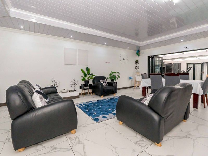 Spacious open-plan living and dining area featuring glossy marble-look floor tiles, recessed downlights, and bi-fold doors leading to the outdoor space.