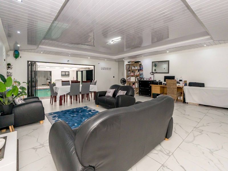 Spacious open-plan living and dining area featuring modern marble-look floor tiles, recessed lighting, and seamless access to the outdoor pool area via stacking doors.