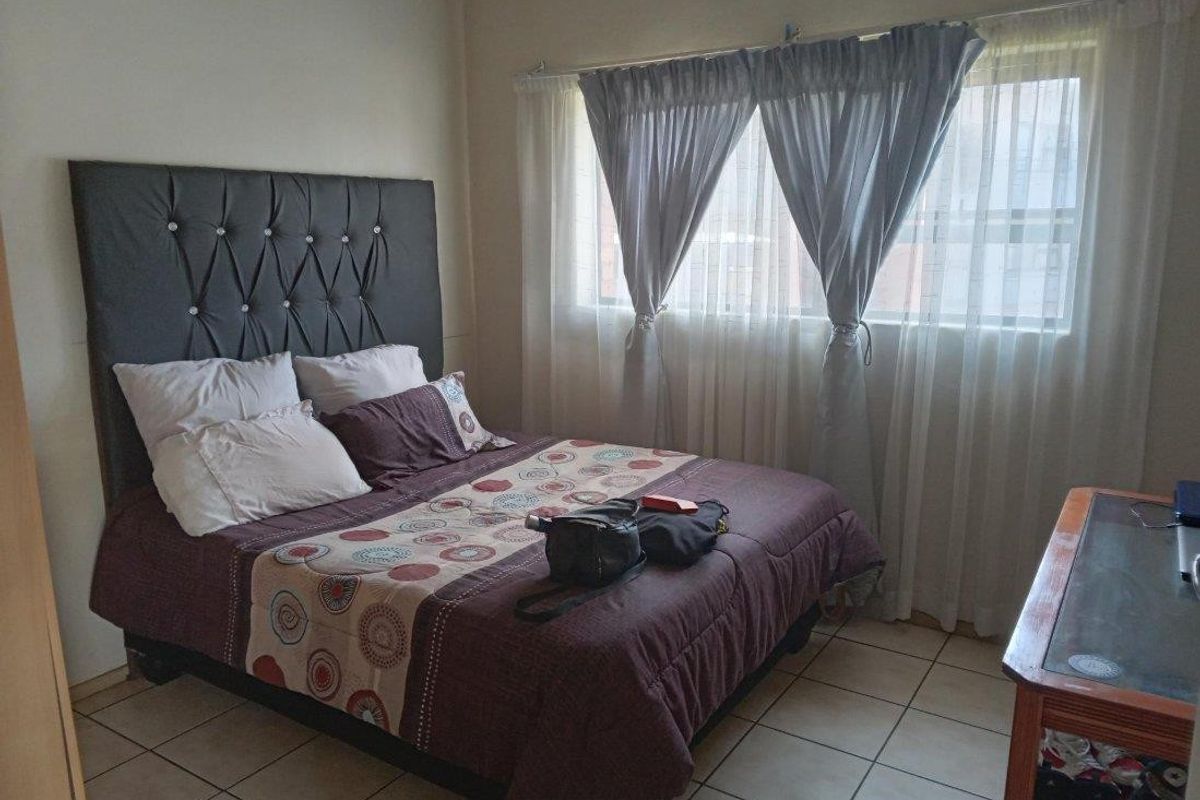 A bedroom featuring tiled flooring and a window with curtain tracks.
