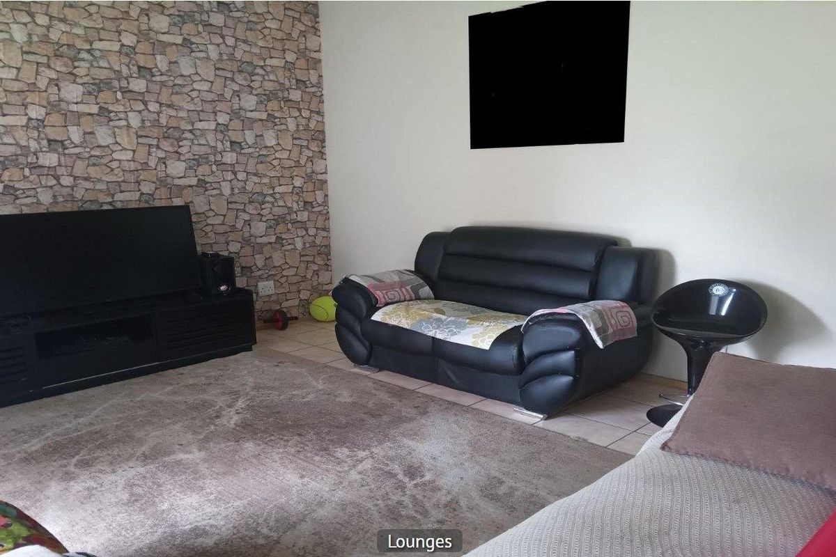 A living room featuring a stone-cladding feature wall and tiled flooring.
