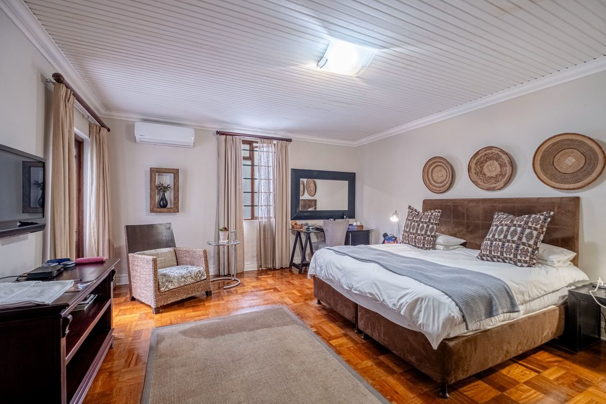 A well-maintained bedroom featuring polished parquet flooring, a tongue-and-groove ceiling, and a wall-mounted air conditioning unit.