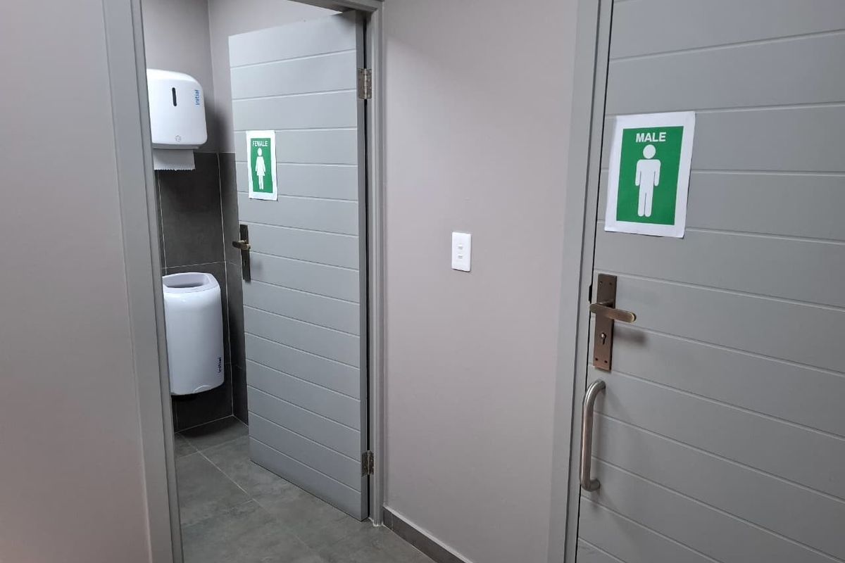 A clean and modern industrial restroom facility featuring clearly marked male and female access doors with contemporary grey finishes.