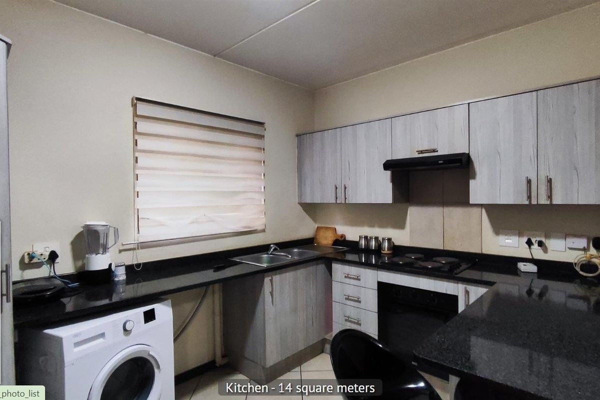 Functional kitchen featuring light wood-grain cabinetry, dark granite countertops, a built-in oven, hob, extractor fan, and dedicated space for a washing machine.