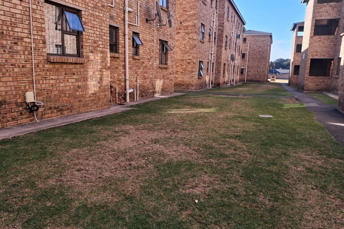 A view of the communal garden area between apartment blocks, featuring face-brick facades and paved walkways.