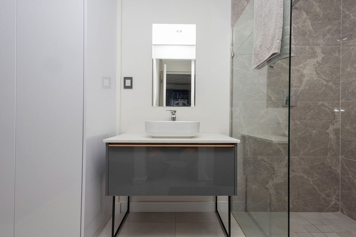Modern bathroom featuring a sleek vanity with a vessel sink, a glass-enclosed walk-in shower with marble-look wall tiles, and contemporary fixtures.