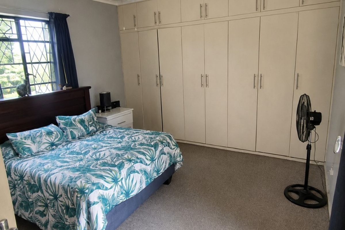 A bedroom featuring extensive built-in floor-to-ceiling cabinetry, a ceiling fan, and carpeted flooring.