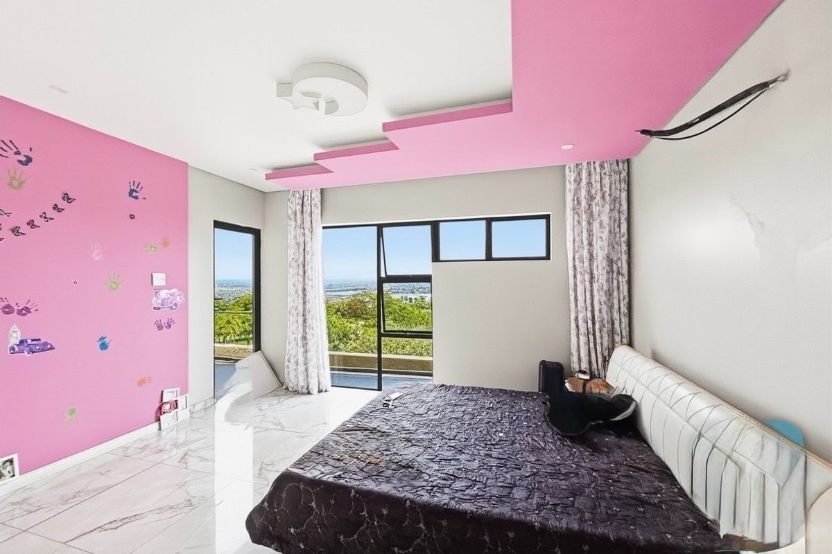 A bedroom featuring large windows with scenic views, marble-look tiled flooring, and a decorative pink recessed ceiling feature.