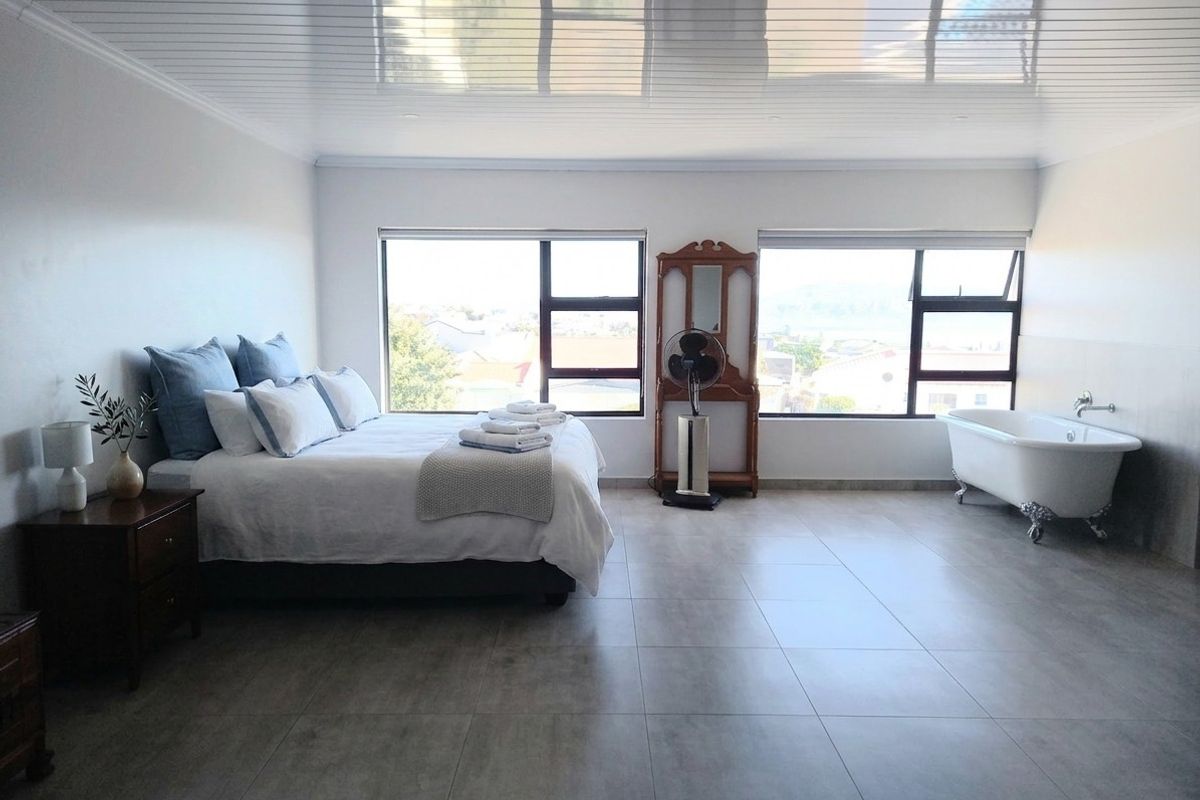 Spacious bedroom featuring large windows, tiled flooring, a glossy ceiling finish, and a classic clawfoot bathtub integrated into the room layout.