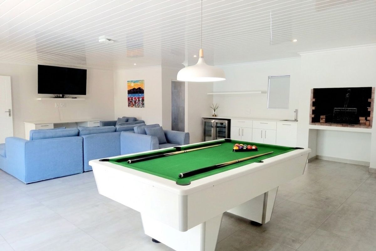 Spacious entertainment area featuring a built-in indoor braai, kitchenette with bar fridge, and ample room for a pool table and lounge seating.