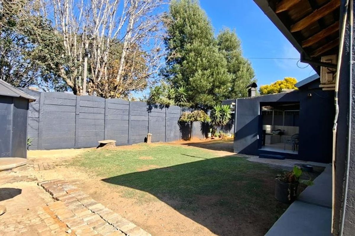 A private rear garden featuring a lawn area, brick paving, and perimeter boundary walling, providing a functional outdoor space.