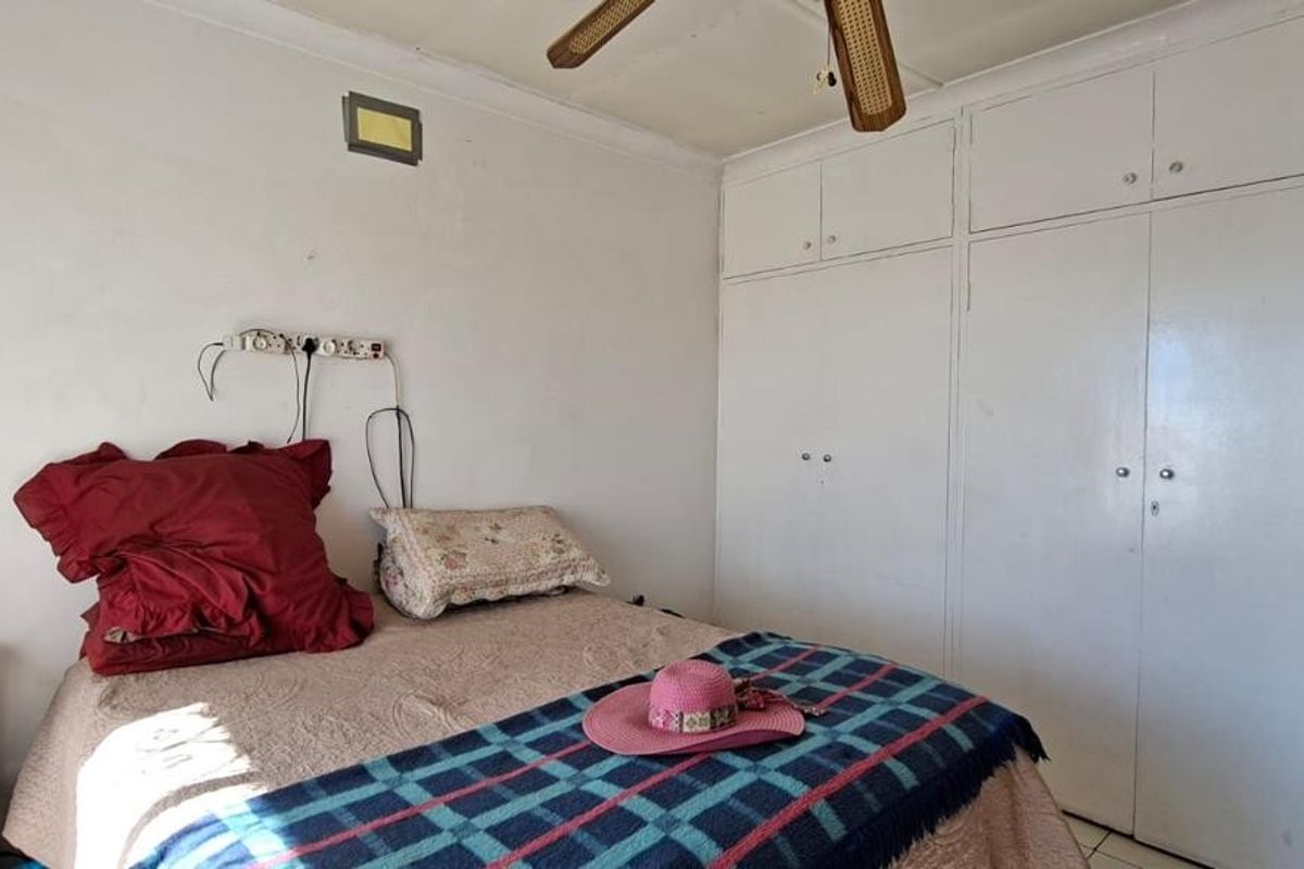 A bedroom featuring built-in cupboards and a ceiling fan, requiring cosmetic updates to the walls and electrical fixtures.