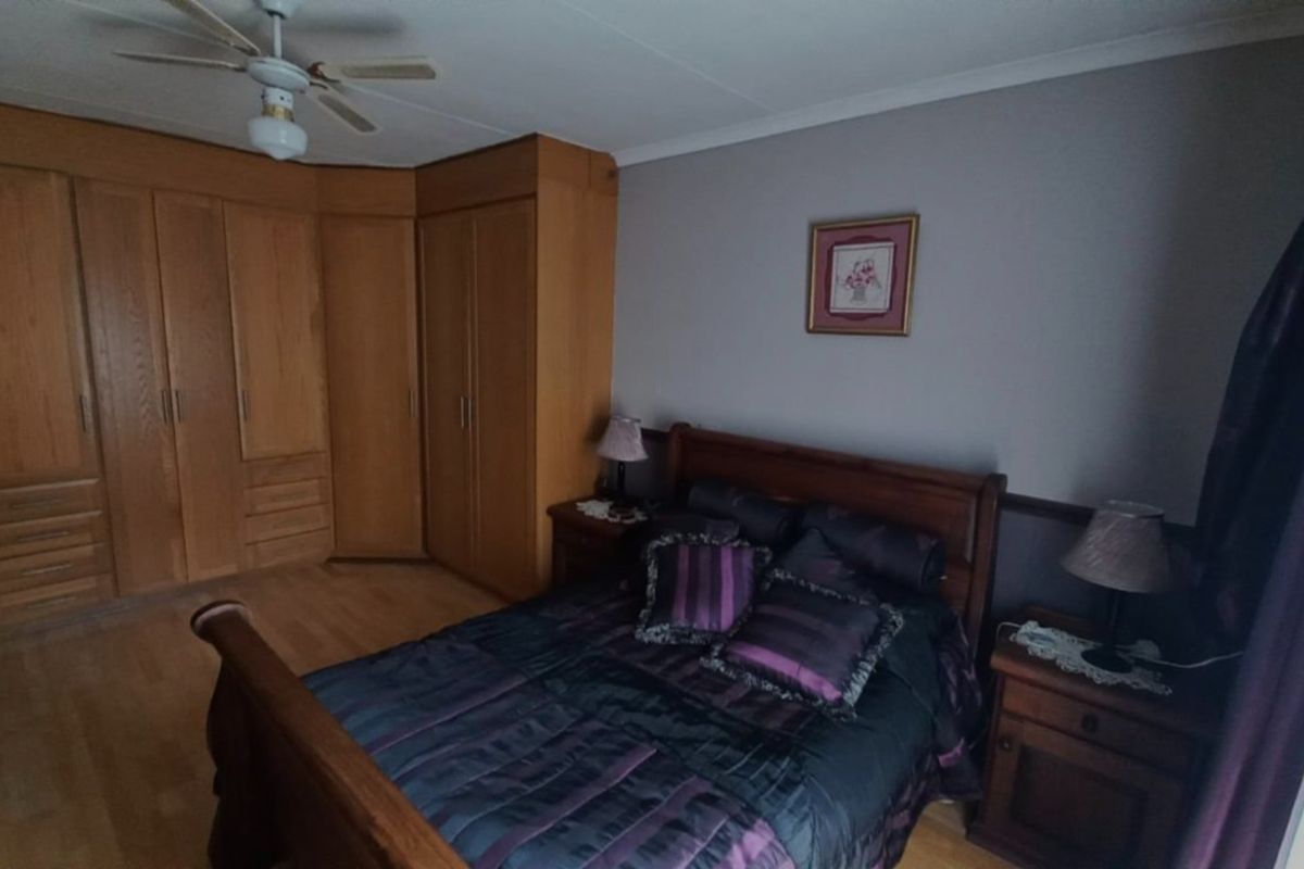 A bedroom featuring built-in wooden cabinetry, laminate flooring, and a ceiling fan.