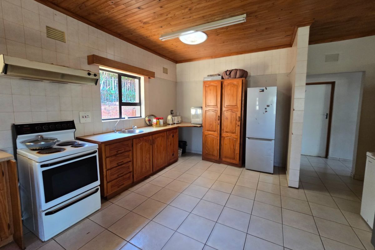 A functional kitchen featuring timber cabinetry, tiled flooring, a built-in stove with extractor fan, and a timber-paneled ceiling.