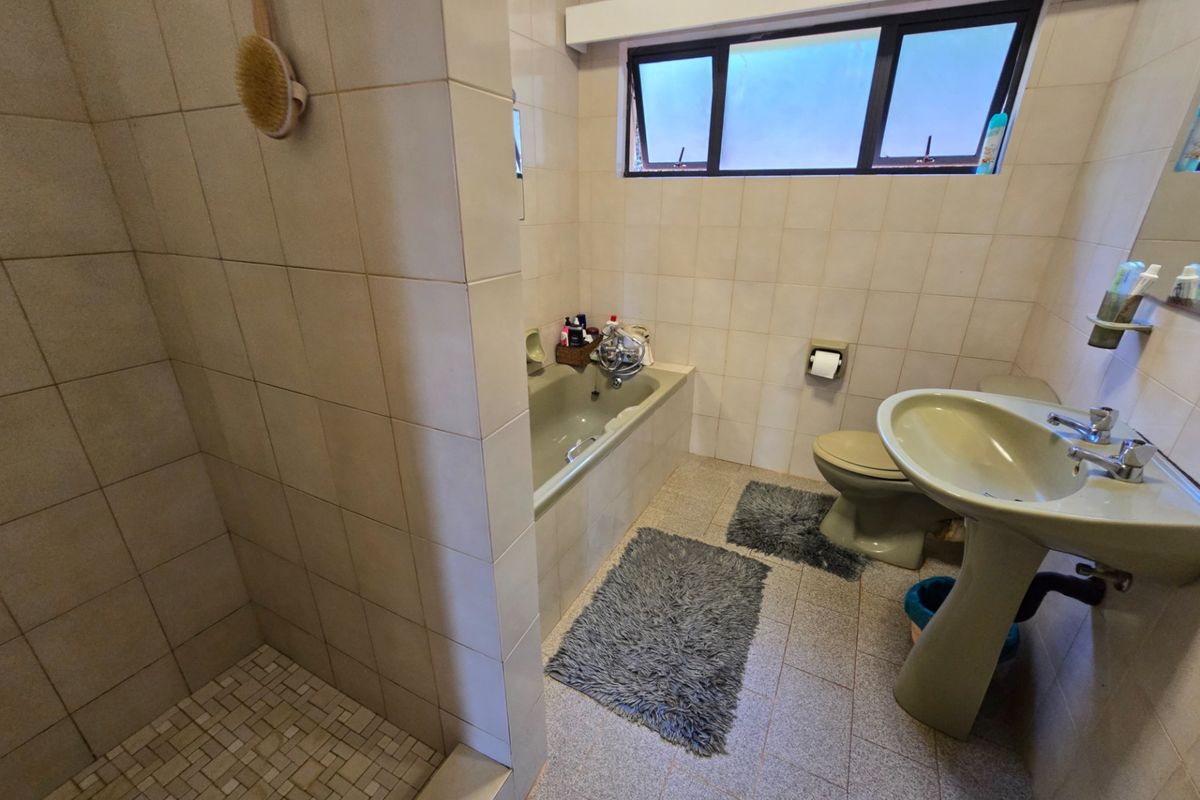 A dated bathroom featuring a separate shower, bathtub, and pedestal basin with neutral wall tiling and tiled flooring.