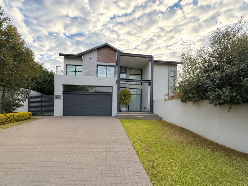 Modern double-story residential home featuring a paved driveway, integrated double garage, and a balcony with contemporary architectural finishes.