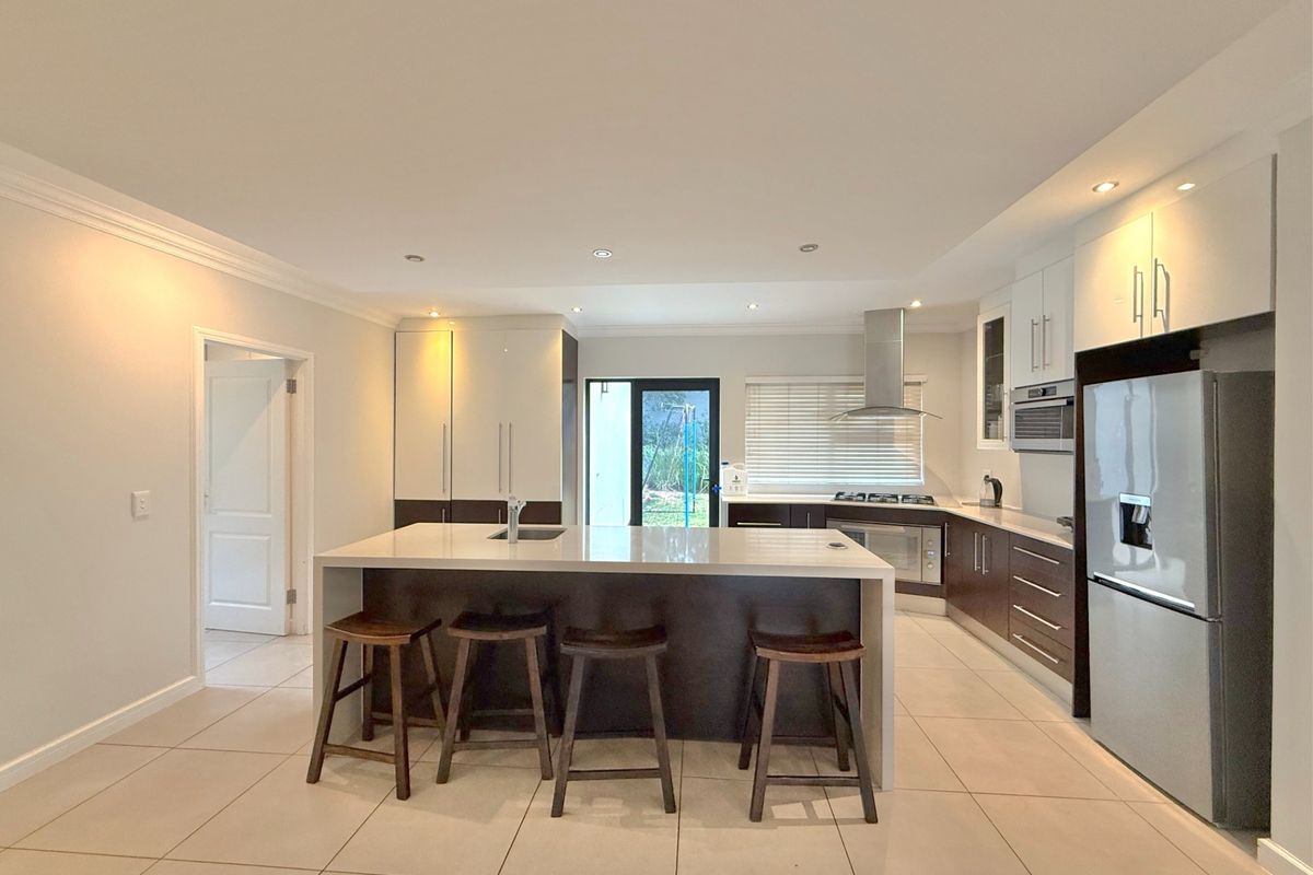 Modern kitchen featuring a central island with stone countertops, dark and white cabinetry, built-in appliances, and tiled flooring with recessed lighting.