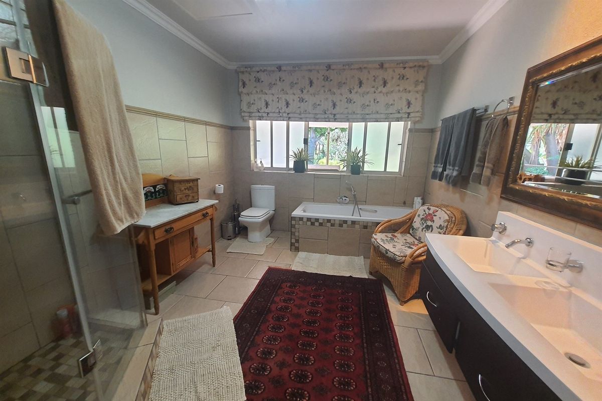 Spacious bathroom featuring a glass-enclosed shower, a built-in bathtub with tiled surround, a double vanity, and a toilet.